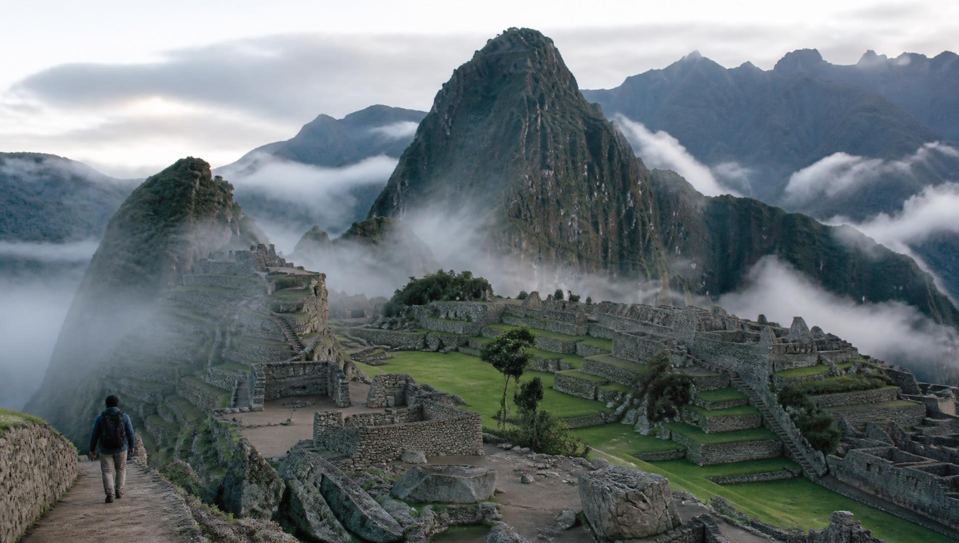 Machu Picchu ao amanhecer entre montanhas com neblina
